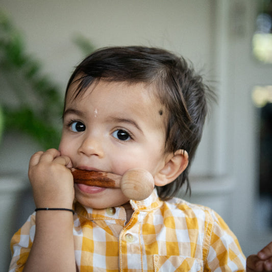 Baby mouthing a wooden teether during sensory play