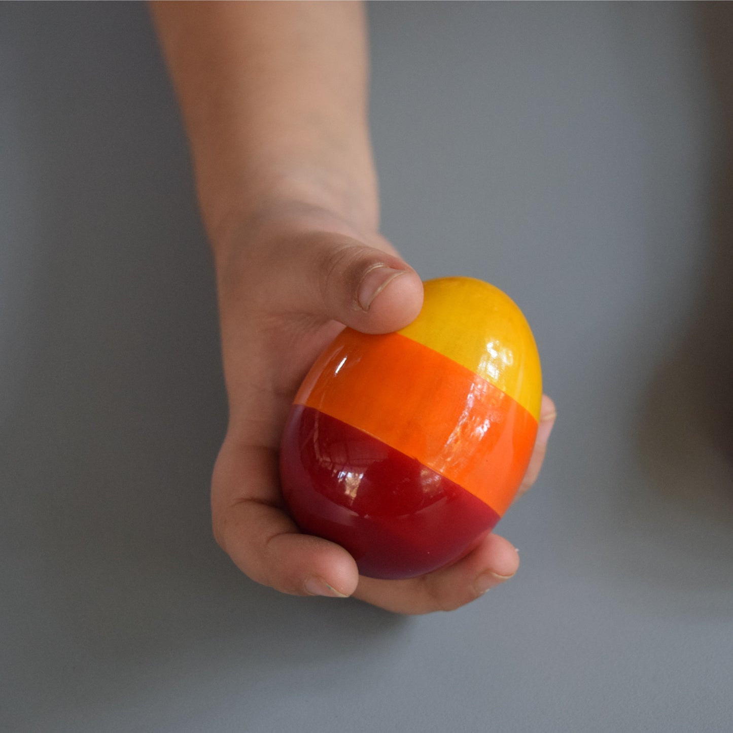 Baby holding Wooden Egg Rattle, easy-grip wooden rattle for sensory play and fine motor skills.