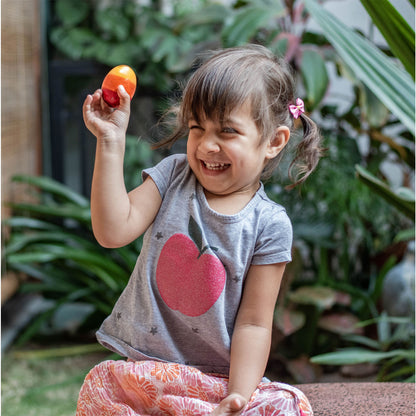 Girl playing with a wooden egg rattle by The Toy Trunk, an eco-friendly wooden rattle toy that encourages sensory exploration, grip strength, and early brain development.