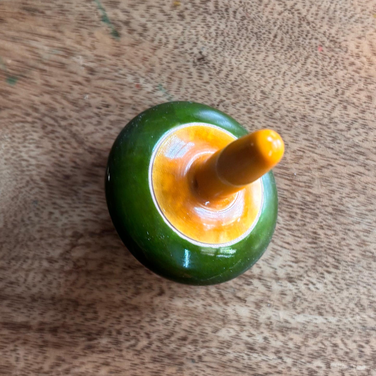 Green and yellow handmade wooden spinning top for screen-free skill play.