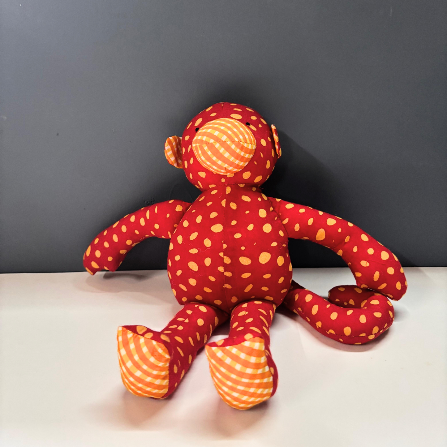 Mimi Monkey cotton soft toy in red and orange spotted handblock print.