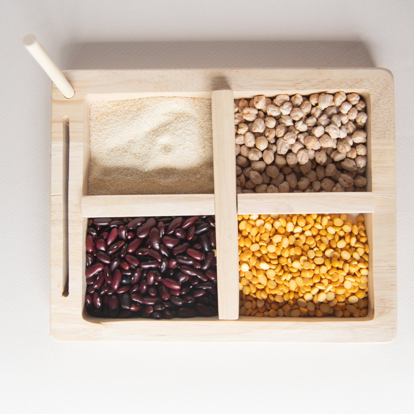 Montessori Wooden Sorting Tray by The Toy Trunk with four compartments for sensory grain play.