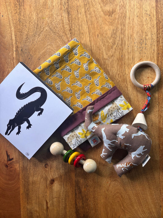 Newborn Gentle Start Gift Set featuring a cotton sleeping mat, elephant cuddle toy with teether, wooden dumbbell rattle, and high-contrast accordion book.