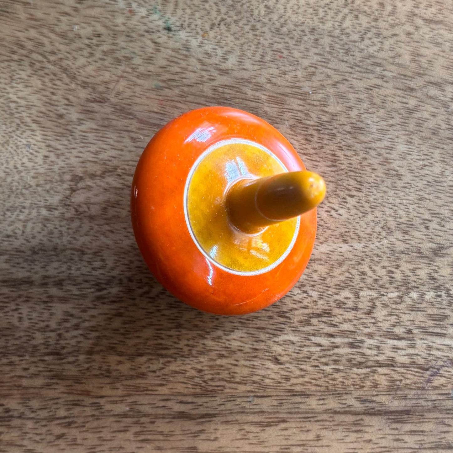 Orange and yellow traditional wooden spinning top for focus and coordination.