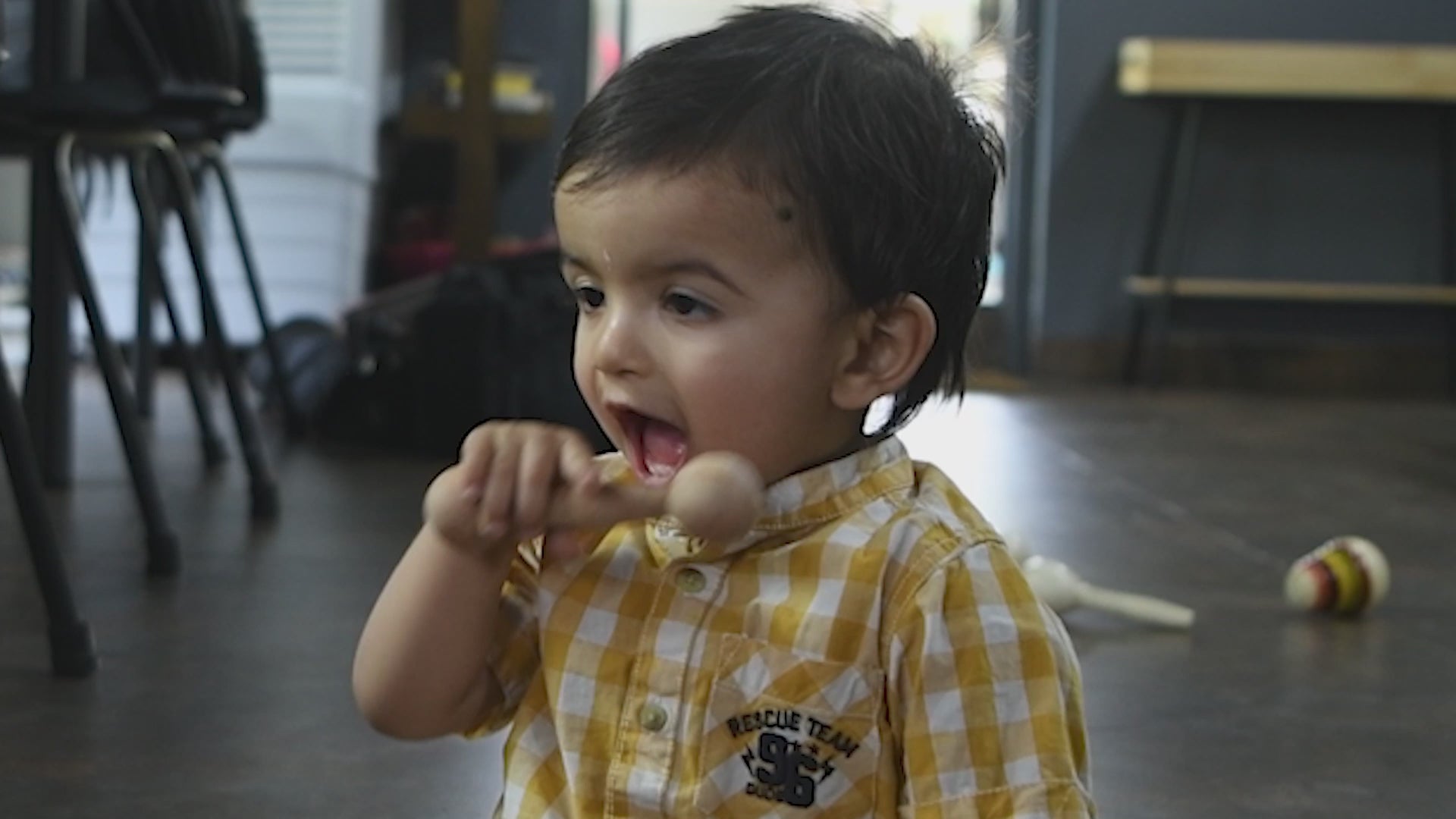 Baby playing with a wooden dumbbell teether by The Toy Trunk