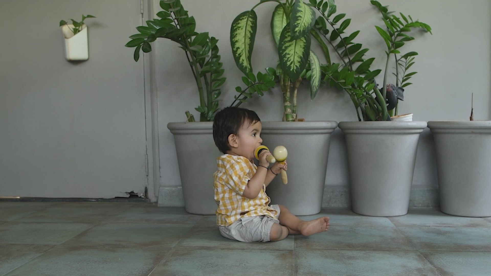 baby playing with wooden maraca rattle