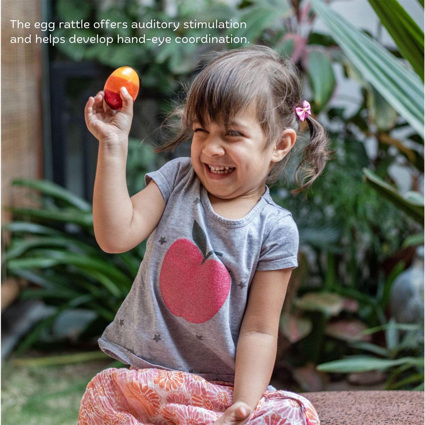 The Toy Trunk baby girl playing with wooden egg rattle for sensory exploration and auditory play