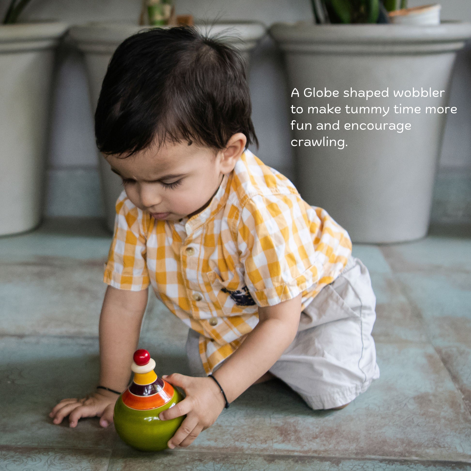 Baby playing with wooden globe wobbler for tummy time and reaching.