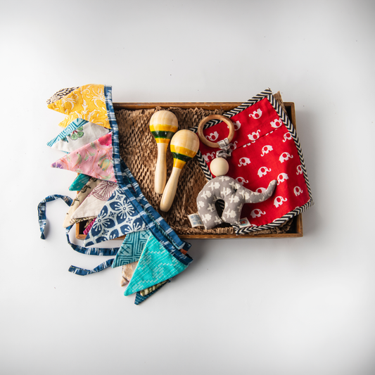 Wooden Sensory Adventure Baby Box with maraca rattles, soft elephant toy, herb bag and bunting.