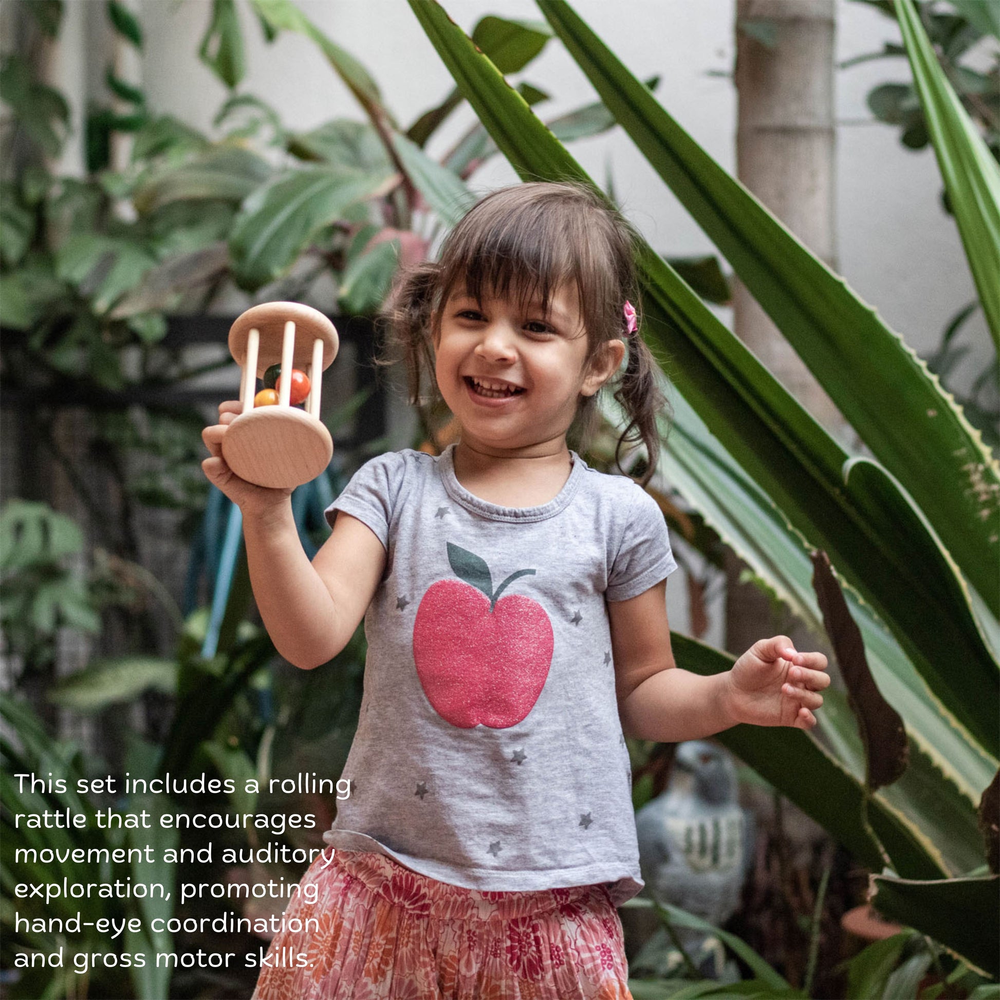 Wooden Cognitive Roll and Learn Set The Toy Trunk – toddler girl playing with rolling rattle to develop gross motor and auditory skills