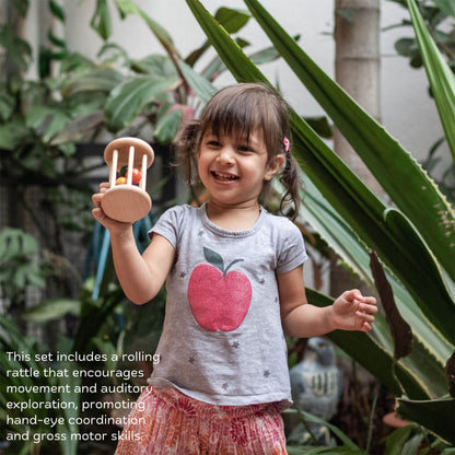 Wooden Cognitive Roll and Learn Set The Toy Trunk – toddler girl playing with rolling rattle to develop gross motor and auditory skills