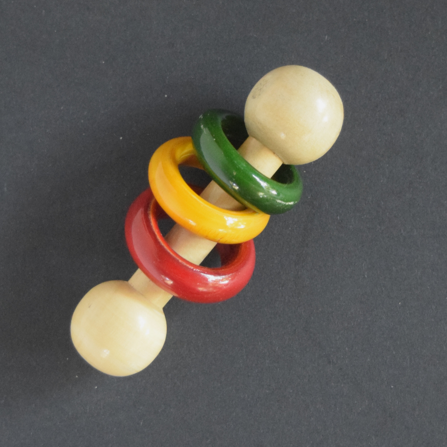 Wooden dumbbell rattle with colorful rings for newborn sound play.