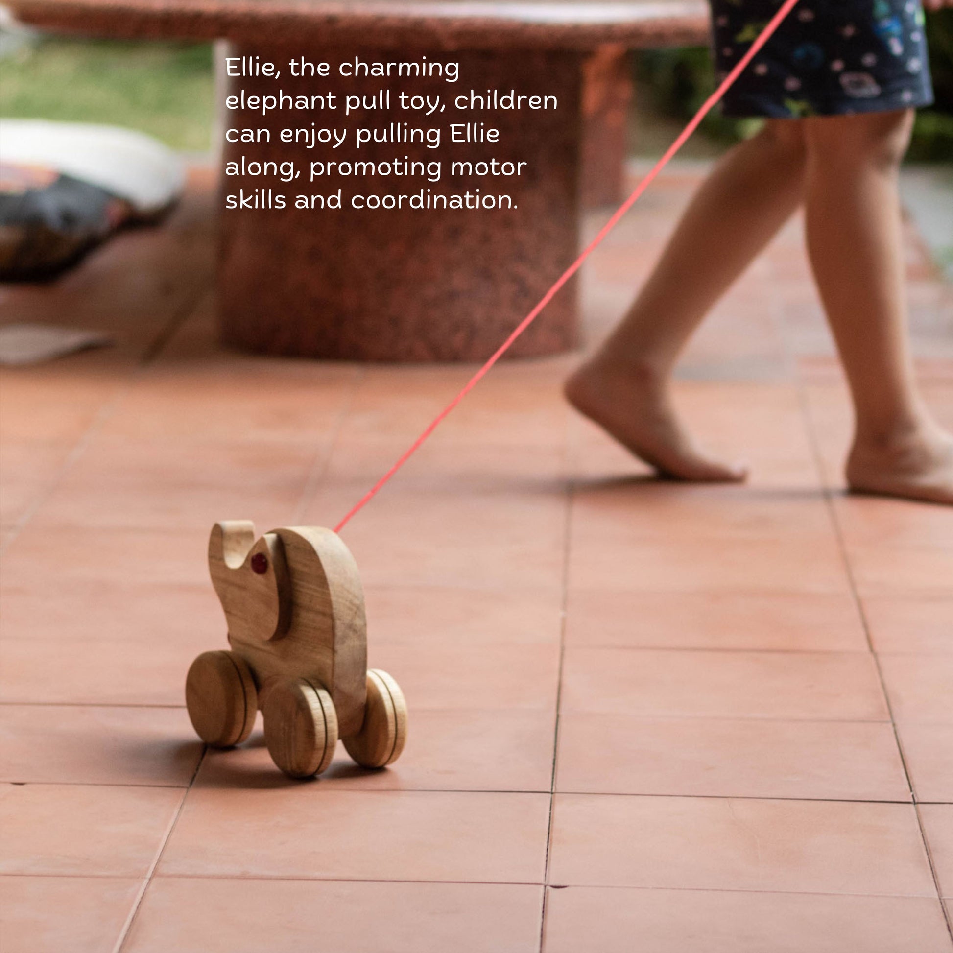 Child pulling Ellie the Elephant wooden toy for walking confidence and gross motor skills.