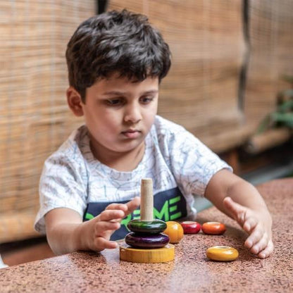 Child playing with wooden ring stacker for fine motor skills and focus.